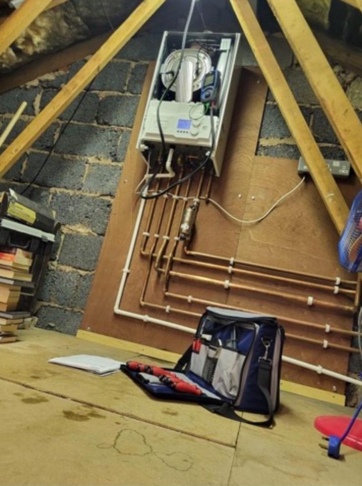 Loft boiler being commissioned with neat copper pipework on a backboard