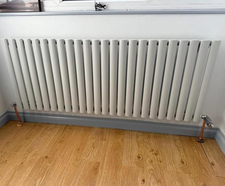 New white column radiator fitted under a window